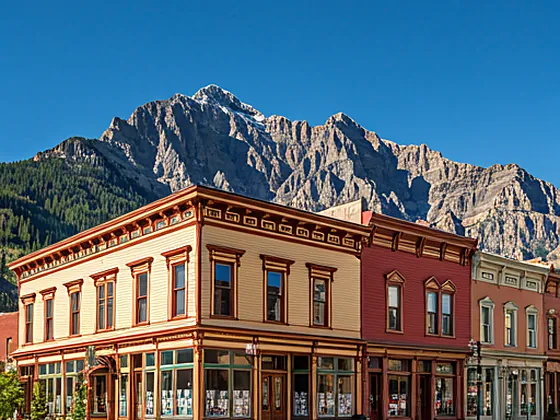 Classic colorful Victorian houses in downtown Telluride with Ajax Peak in the background under a clear blue sky