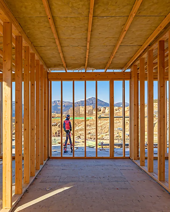 Interior of a luxury modern timber frame home under construction with professional insulation installation visible in the wall cavities